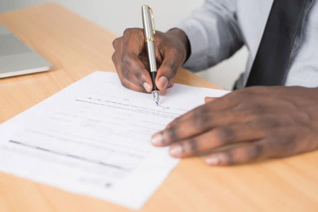 Photo of a person signing a filled-out form