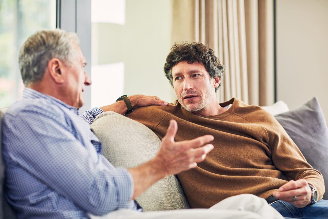 Younger man and older man talking on a couch