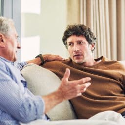 Younger man and older man talking on a couch