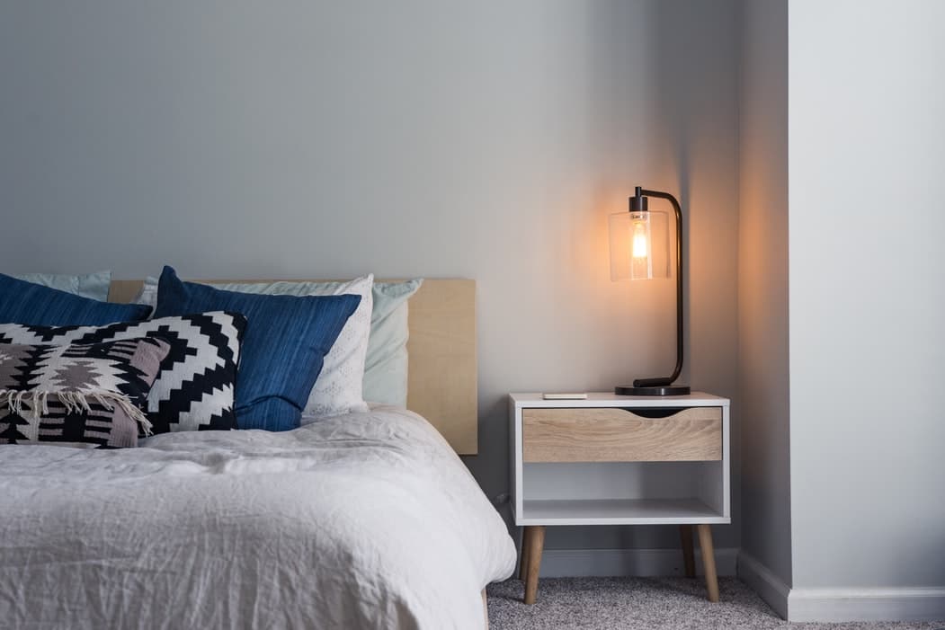 A bed and nightstand with a light.
