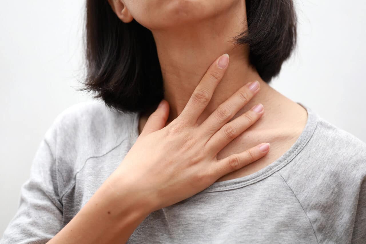 Close up of a woman touching her throat.