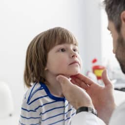 Doctor checking tonsils of patient at hospital