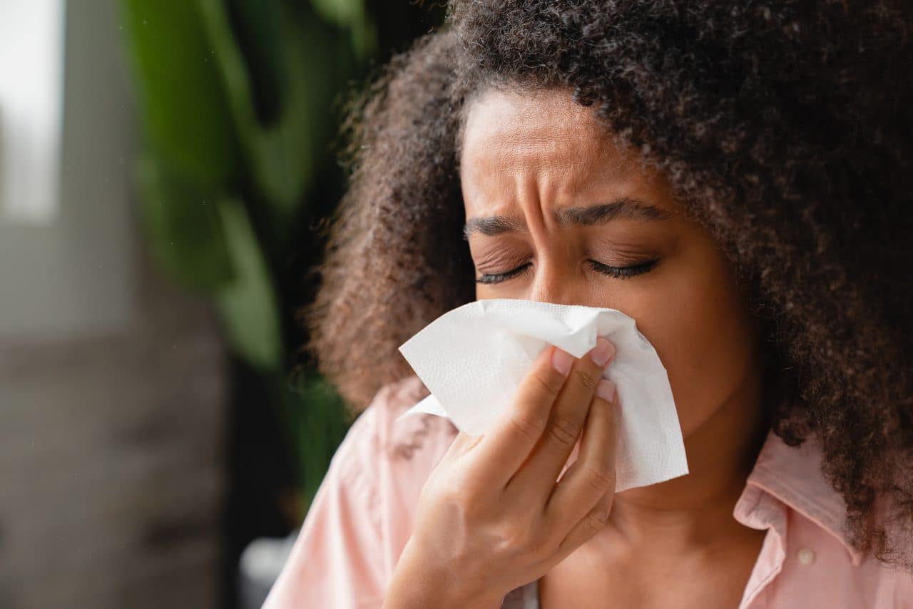 Woman with a sinus infection blowing her nose.