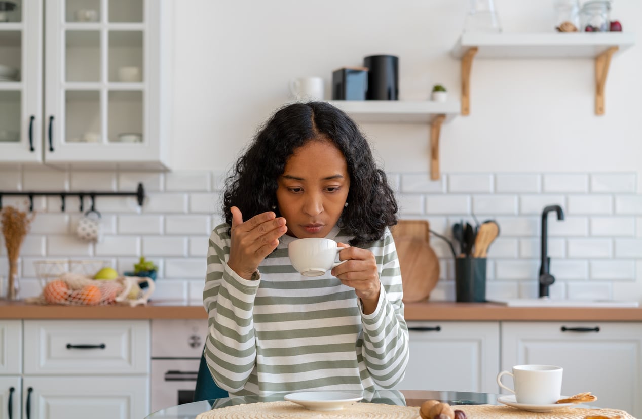 Woman having trouble smelling her morning cup of coffee.