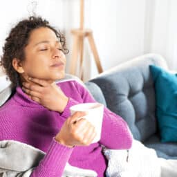 Woman with sore throat sips tea