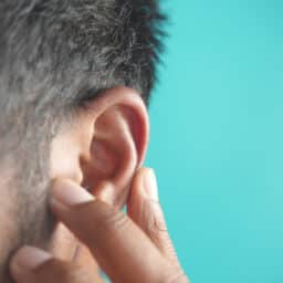Person with ear pain touches ear