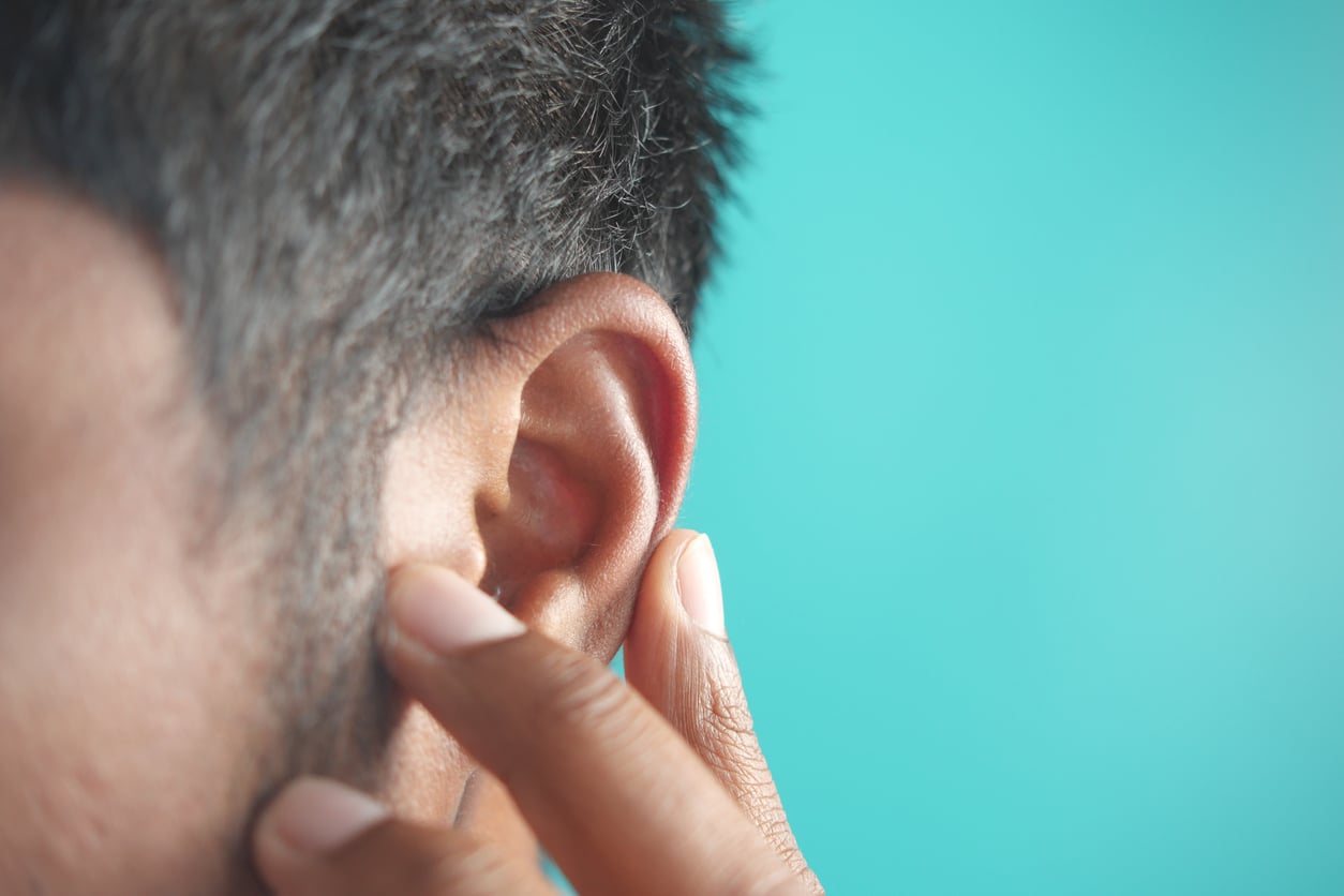 Person with ear pain touches ear