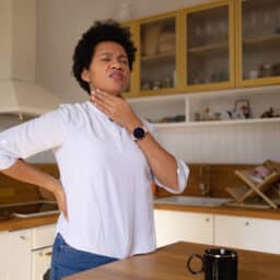 Woman with a sore throat holding her throat.