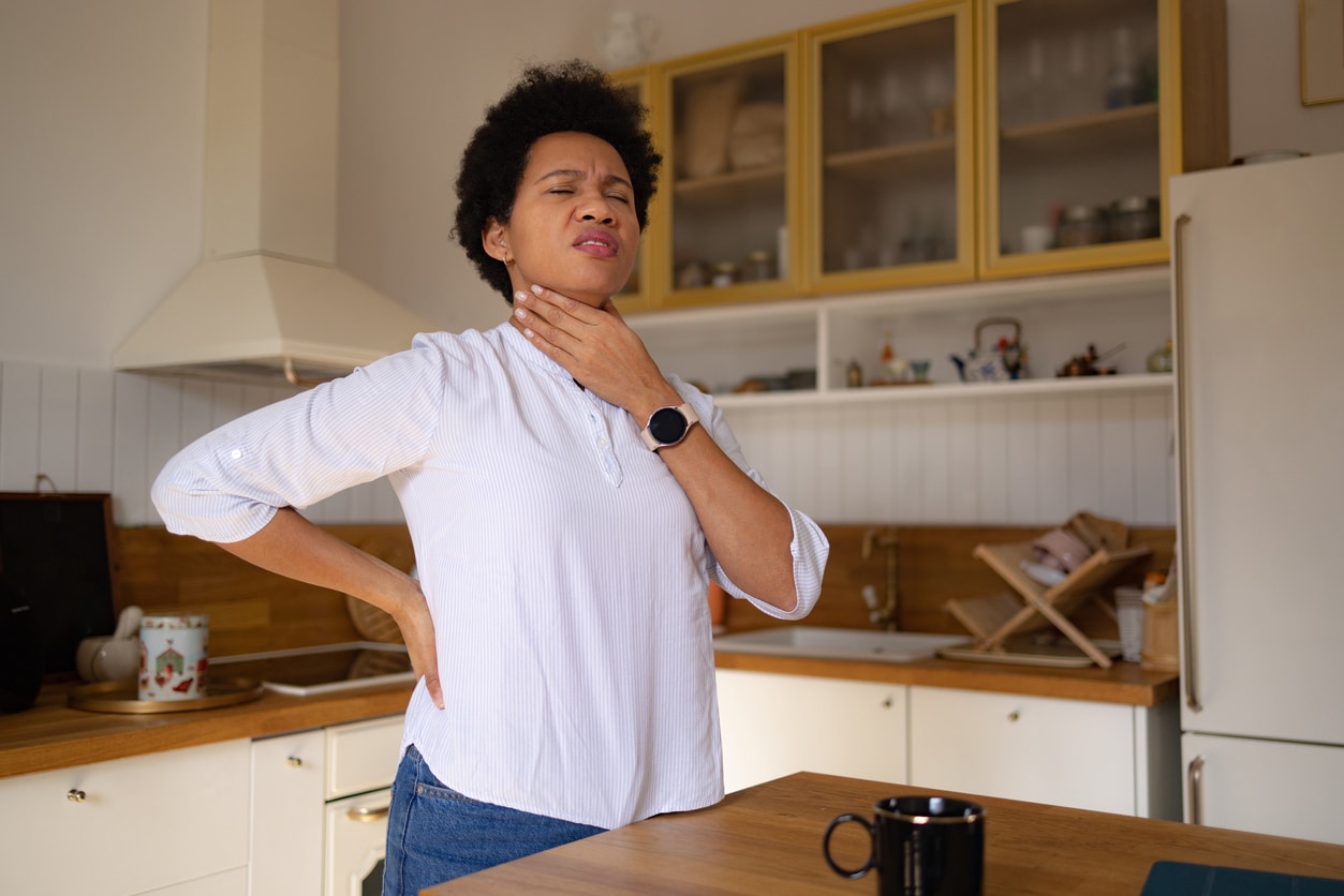 Woman with a sore throat holding her throat.