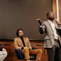 A person delivers a speech in front of a panel.